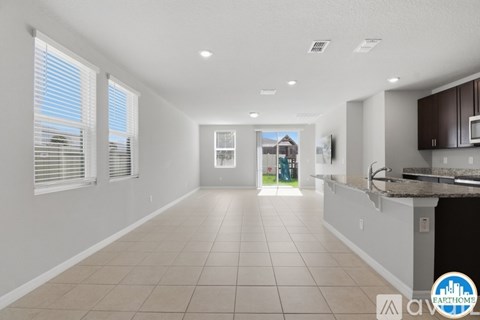 A spacious kitchen and living room with a view of a house through the window.