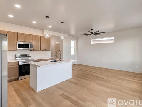 A modern kitchen with wooden floors and a white island.