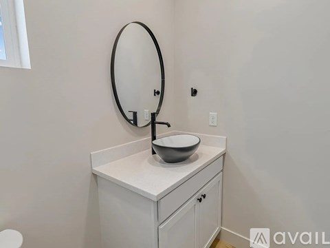 A bathroom vanity with a bowl sink and a round mirror.