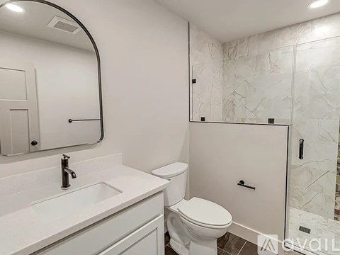 A white bathroom with a marble wall and a round mirror.