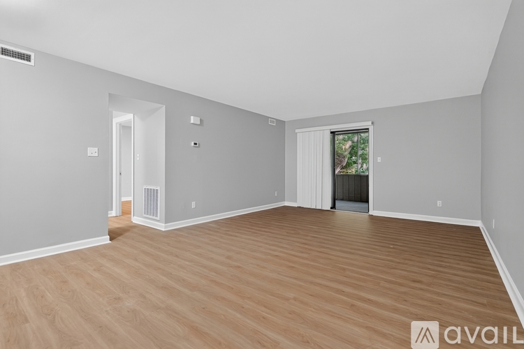 A spacious room with wooden flooring and white walls.