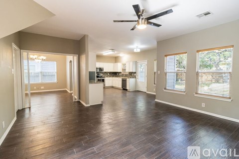 A spacious living room with hardwood floors and a ceiling fan.