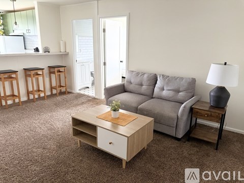 A living room with a grey couch, a wooden coffee table, and a lamp on a side table.