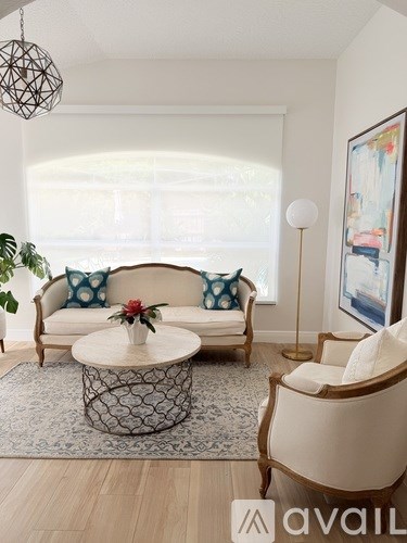 A living room with a white sofa, a coffee table, and a painting on the wall.