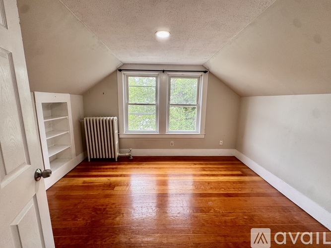A room with wooden floors and a window with a view of trees.