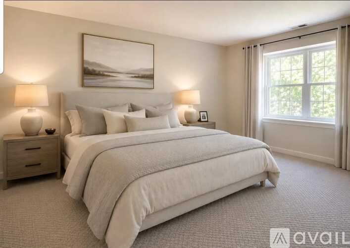 A bedroom with a large bed, two lamps, and a painting on the wall.