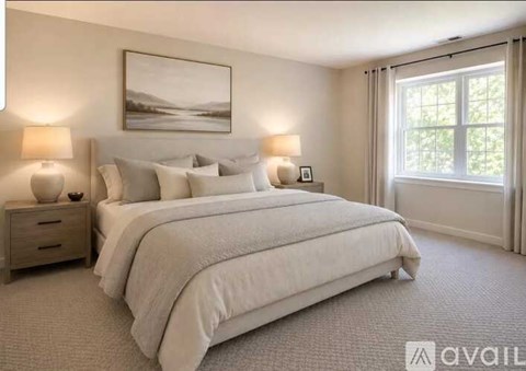 A bedroom with a large bed, two lamps, and a painting on the wall.