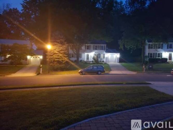 A car is parked on a street at night with houses on both sides.