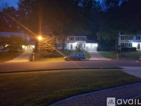 A car is parked on a street at night with houses on both sides.