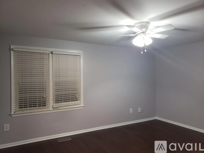 A room with a ceiling fan and a window with blinds.
