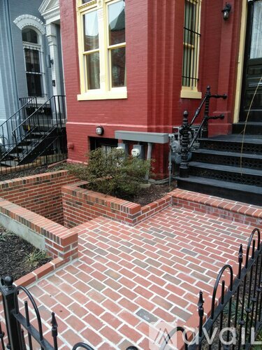 A red brick walkway leads to a black staircase.