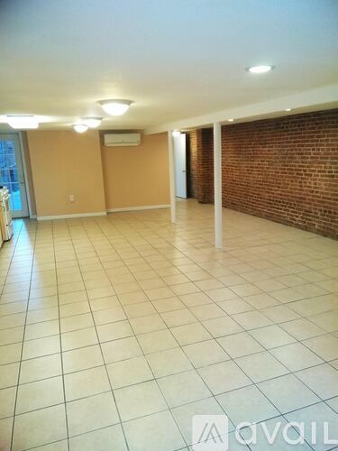A spacious room with tiled flooring and a brick wall.