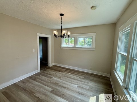 A room with wooden flooring and a chandelier.