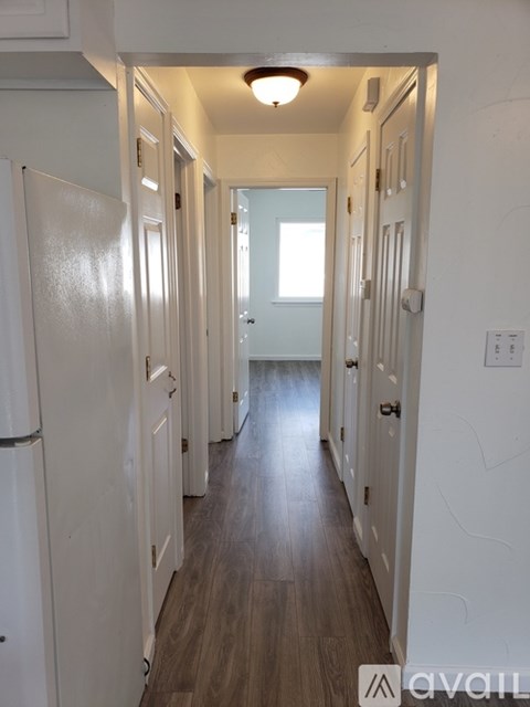 A long hallway with white doors and a wooden floor.