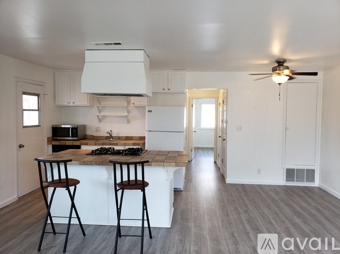 A kitchen with white cabinets and a wooden island with two chairs.