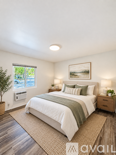 A bedroom with a large bed, a window, and a painting on the wall.
