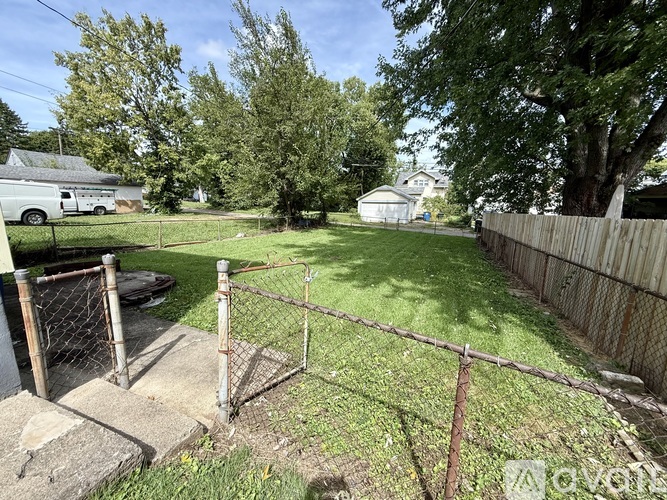 A backyard with a fence and a tree.