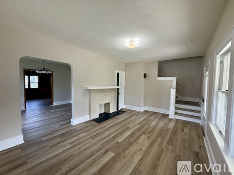 A spacious room with wooden flooring and a fireplace.