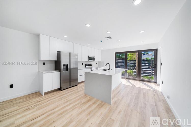 A modern kitchen with wooden floors and white walls.