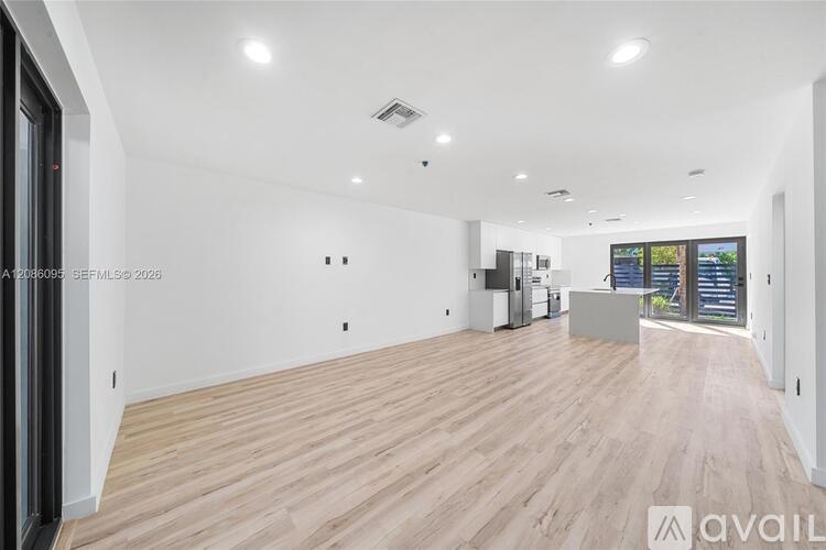 A spacious room with wooden flooring and white walls.