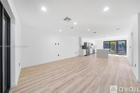 A spacious room with wooden flooring and white walls.
