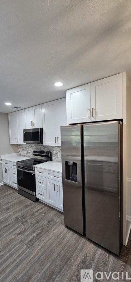 A modern kitchen with a stainless steel refrigerator and white cabinets.
