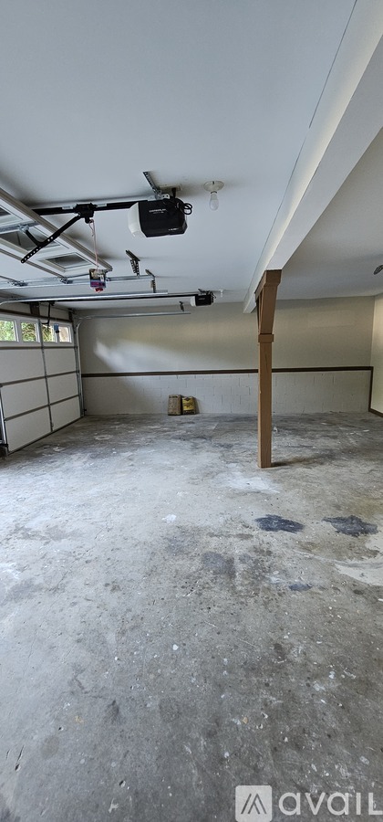 A room with a concrete floor and a white ceiling with a black object hanging from it.
