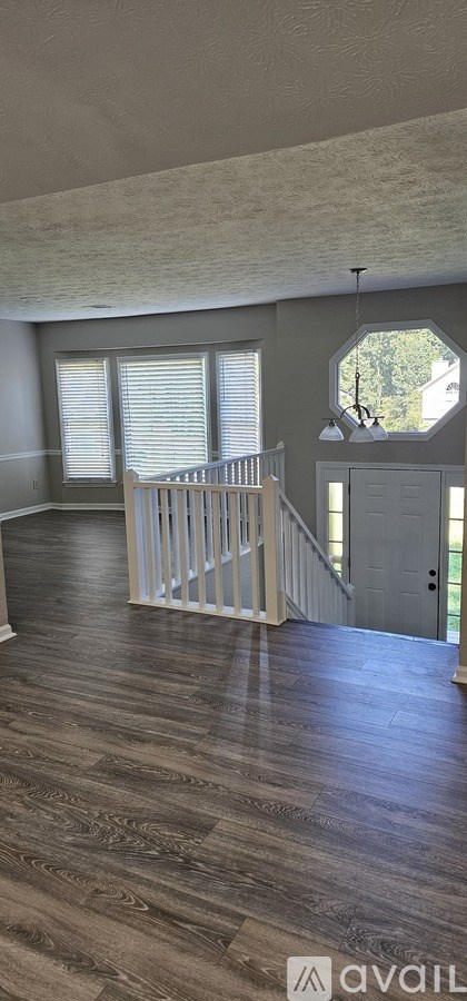 A spacious room with wooden flooring and a staircase.