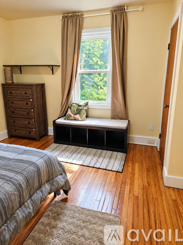 A bedroom with a bed, dresser, and window seat.