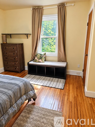A bedroom with a bed, dresser, and window seat.