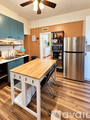 A kitchen with a wooden table and a stainless steel refrigerator.