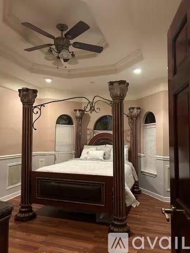 A bedroom with a large bed and a ceiling fan.