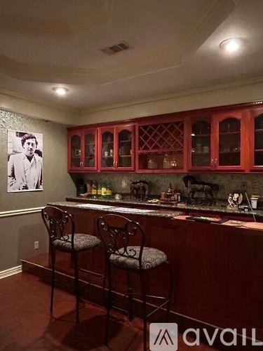 A kitchen with red cabinets and a bar area with two stools.