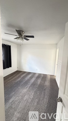 A room with a ceiling fan and a carpeted floor.