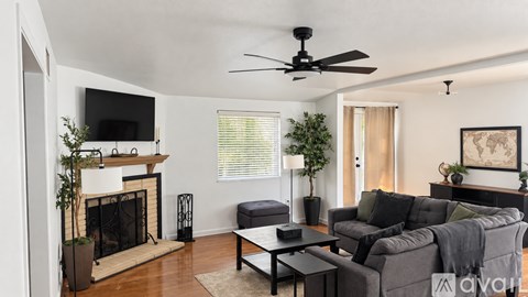 A living room with a grey couch, a fireplace, and a ceiling fan.