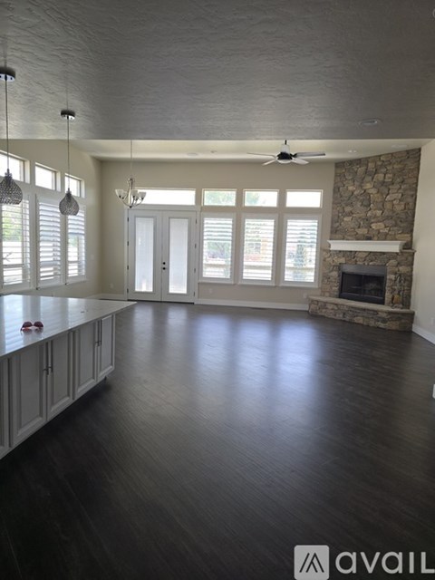 A spacious living room with a fireplace and a ceiling fan.