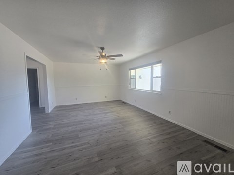 A spacious room with a ceiling fan and wooden flooring.
