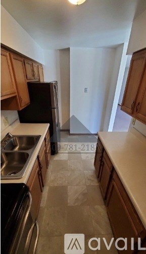 A kitchen with brown cabinets and a black fridge.