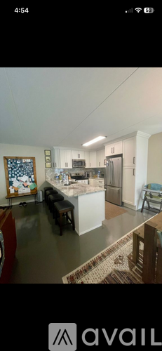 A kitchen with a refrigerator, sink, and a dining table with chairs.