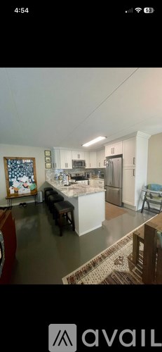 A kitchen with a refrigerator, sink, and a dining table with chairs.
