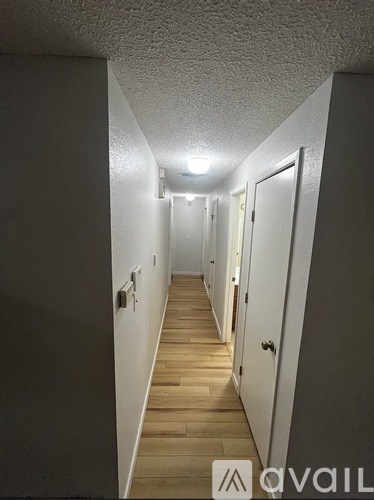 A long hallway with white walls and wood flooring.