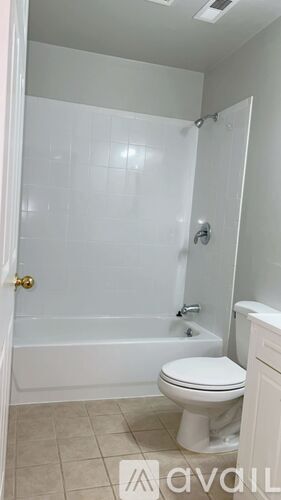A white toilet is in a bathroom with a white tub and shower.