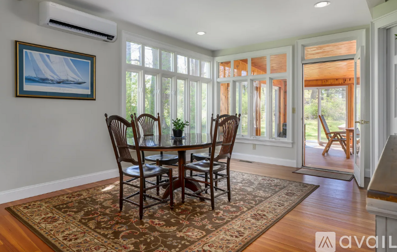 A dining room with a table and chairs and a painting on the wall.