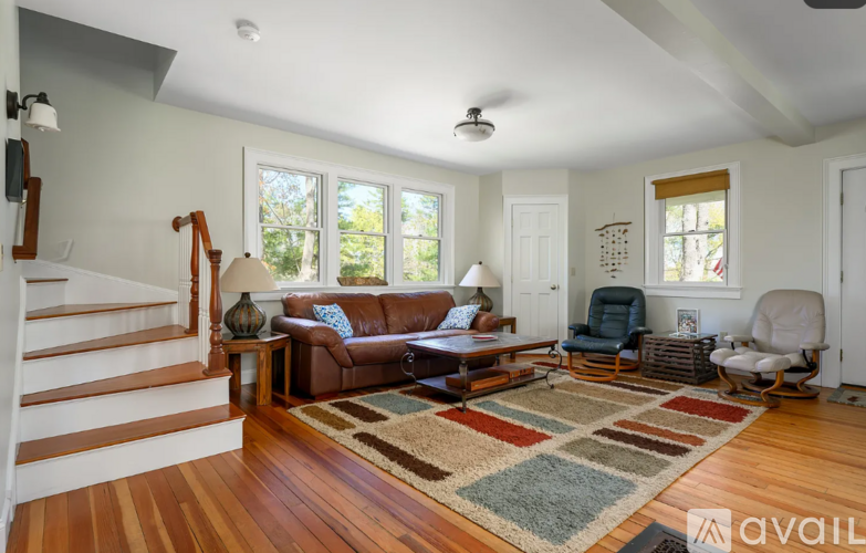 A living room with a brown couch and a rug.