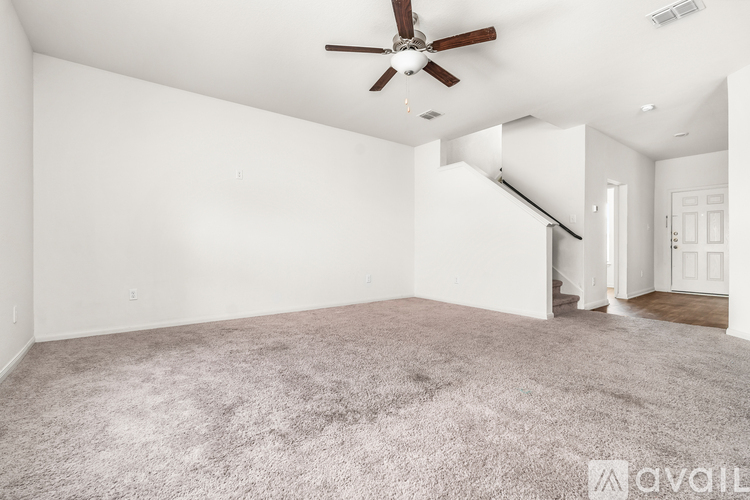 A spacious room with a ceiling fan and carpeted floor.