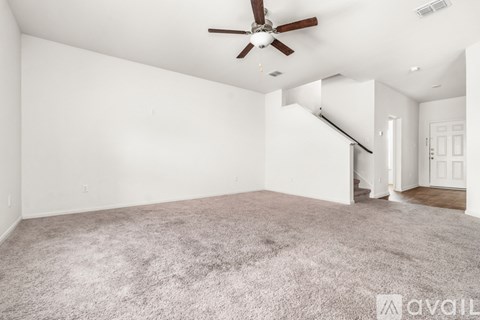 A spacious room with a ceiling fan and carpeted floor.
