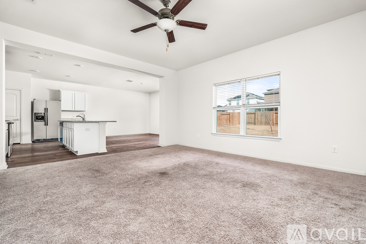 A spacious living room with a ceiling fan and a large window.