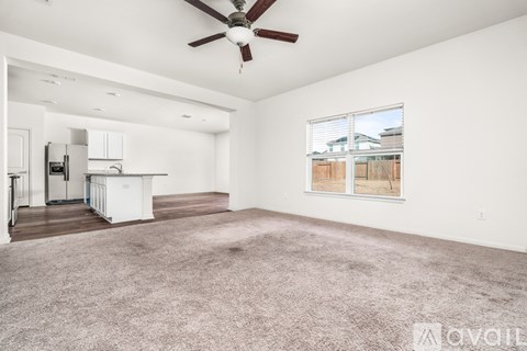 A spacious living room with a ceiling fan and a large window.