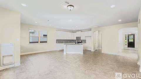 A spacious room with a kitchen area and a refrigerator.