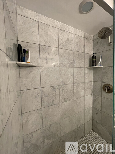A bathroom with a marble tile wall and a glass shower door.